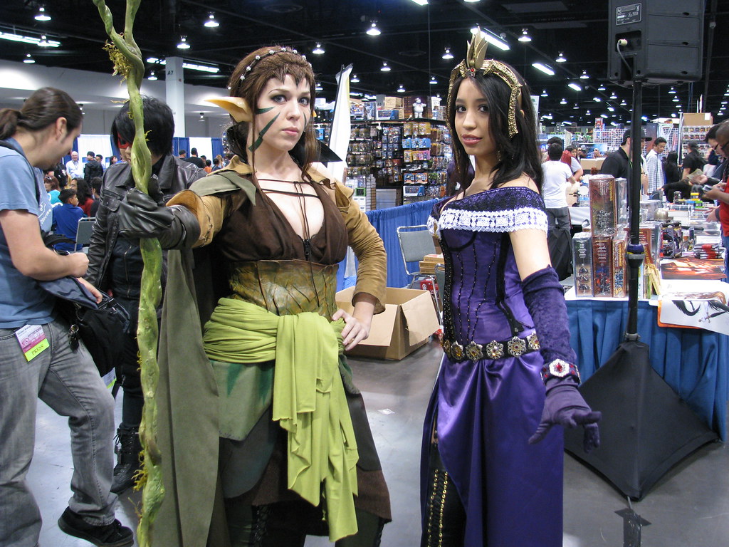 Two Magic: The Gathering planeswalker cosplayers on a busy convention show floor